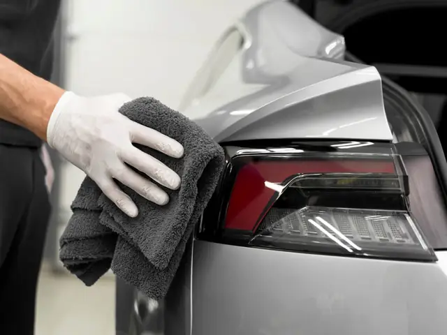 Detailer drying a silver car with a microfiber towel